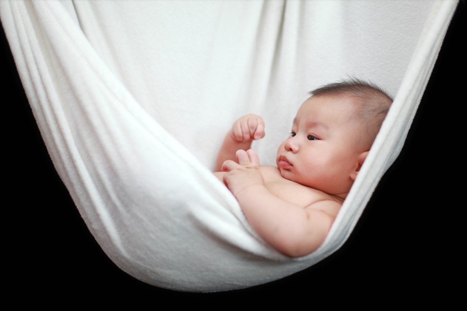 Baby lying in a white hammock sling